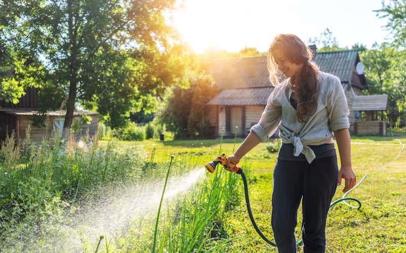 woman watering her garden at the house she bought with her USDA loan