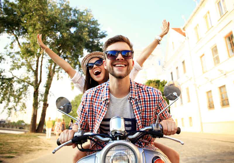 happy couple riding on scooter on a vacation they funded with their class act personal loan